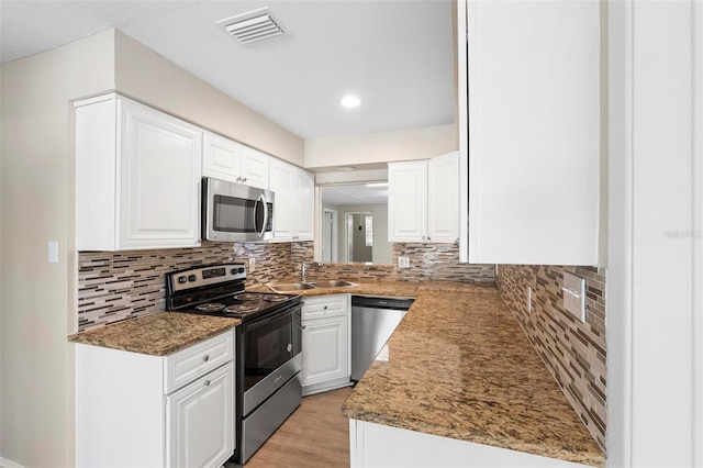 kitchen with sink, tasteful backsplash, light hardwood / wood-style flooring, white cabinets, and appliances with stainless steel finishes