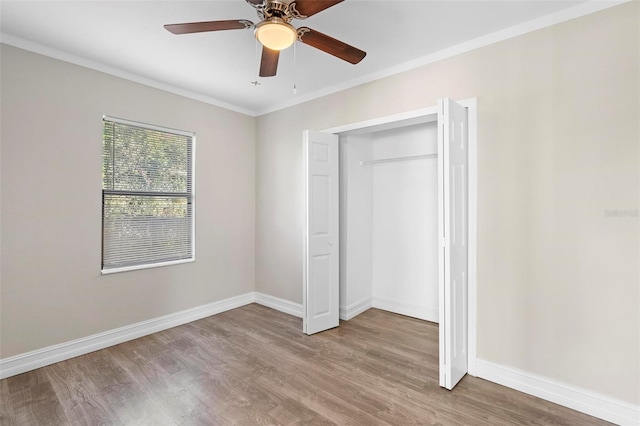 unfurnished bedroom with light wood-type flooring, a closet, ceiling fan, and crown molding