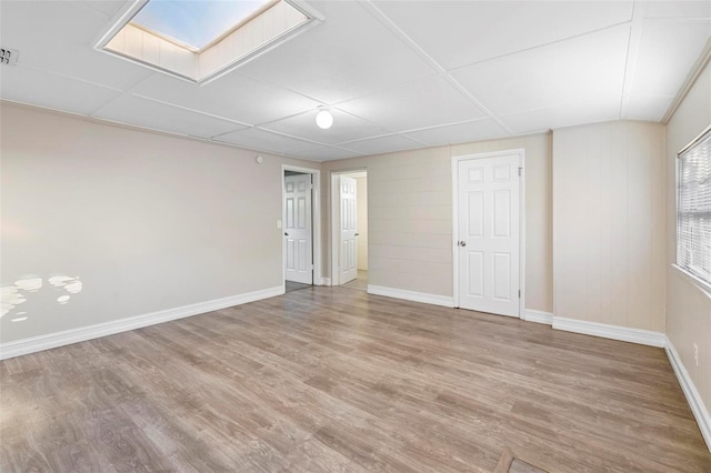 empty room with wood-type flooring and a skylight