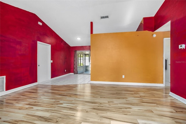 empty room with light wood-type flooring and high vaulted ceiling