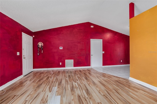 interior space with a textured ceiling, light hardwood / wood-style floors, and vaulted ceiling