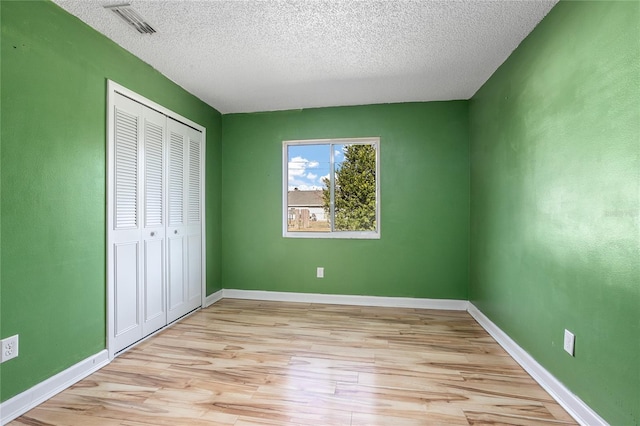 unfurnished bedroom featuring a textured ceiling, light wood-type flooring, and a closet