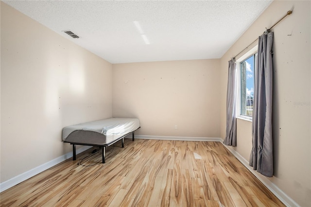 bedroom featuring light wood-type flooring and a textured ceiling