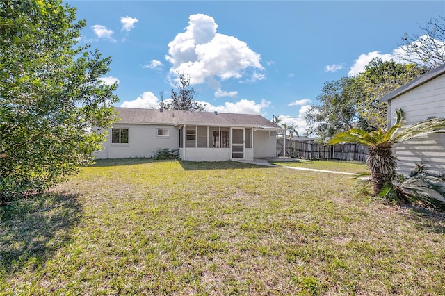 back of property with a lawn and a sunroom