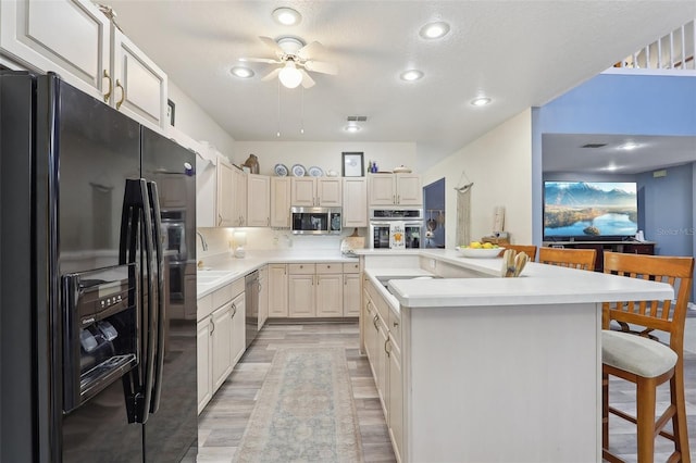 kitchen featuring a kitchen bar, appliances with stainless steel finishes, a kitchen island with sink, ceiling fan, and sink