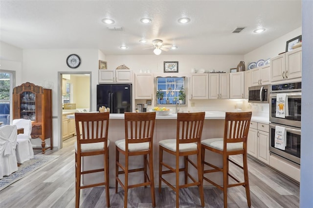 kitchen with a breakfast bar, light hardwood / wood-style flooring, a kitchen island, and stainless steel appliances