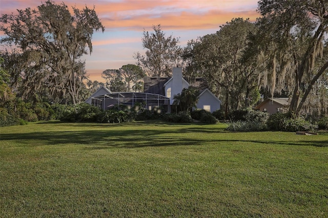 yard at dusk featuring glass enclosure