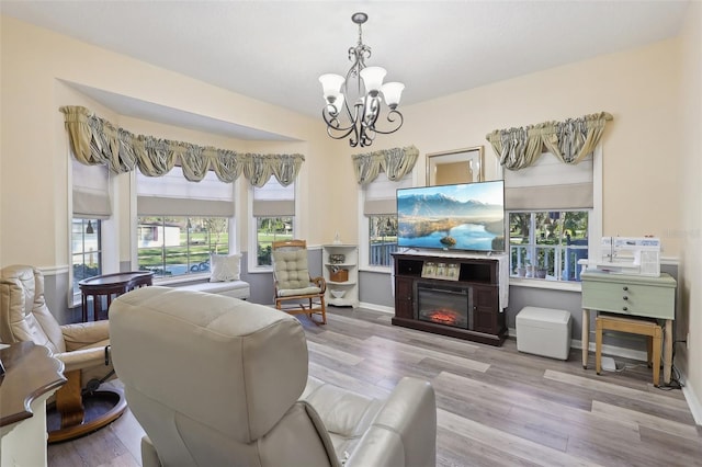 living room featuring light wood-type flooring, an inviting chandelier, and plenty of natural light