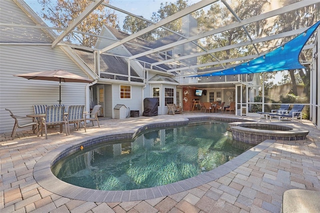 view of pool featuring glass enclosure, an in ground hot tub, and a patio area