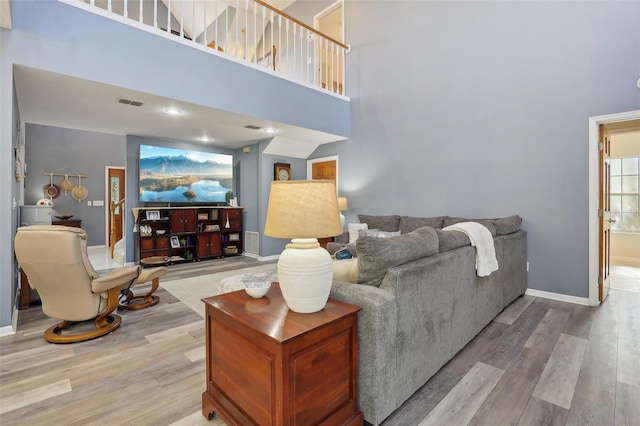 living room with a towering ceiling and hardwood / wood-style flooring