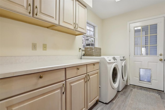 laundry area with cabinets, light wood-type flooring, and washing machine and clothes dryer