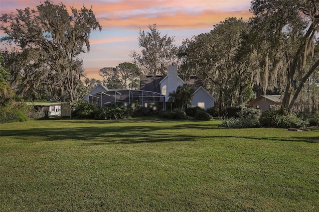 yard at dusk featuring a lanai