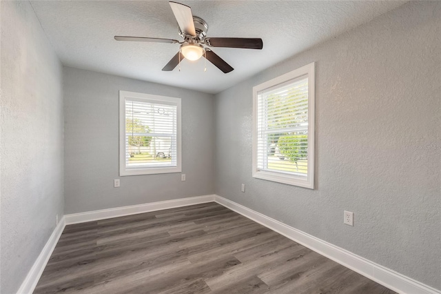 empty room with ceiling fan, a healthy amount of sunlight, dark hardwood / wood-style flooring, and a textured ceiling