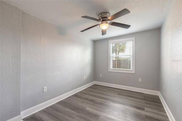 empty room featuring ceiling fan, dark wood-type flooring, and a textured ceiling