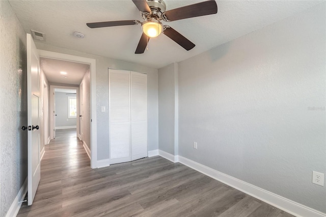 unfurnished bedroom featuring hardwood / wood-style floors, ceiling fan, and a closet