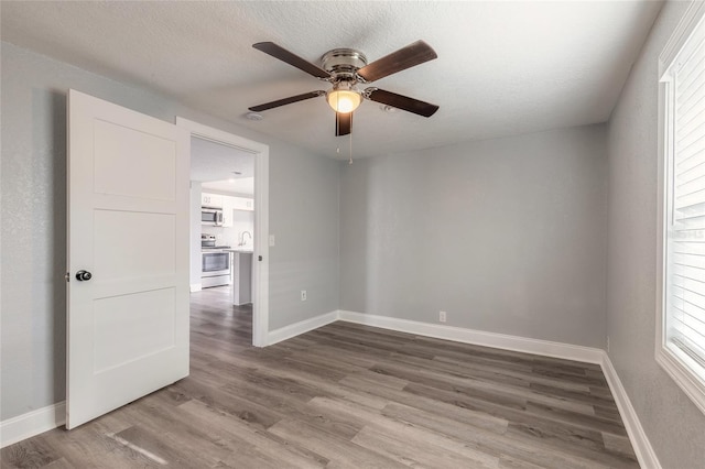 spare room featuring hardwood / wood-style floors, ceiling fan, sink, and a textured ceiling