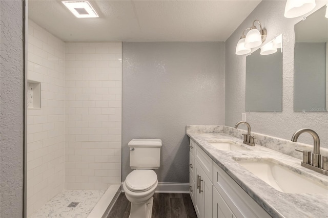 bathroom with vanity, toilet, wood-type flooring, and tiled shower