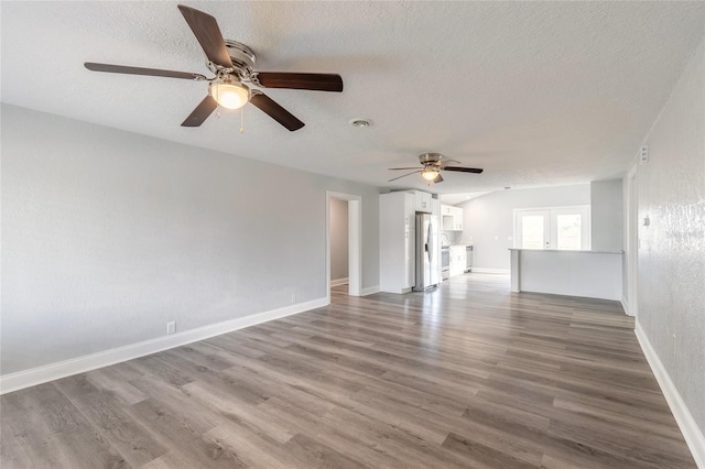 unfurnished living room featuring ceiling fan, hardwood / wood-style floors, and a textured ceiling