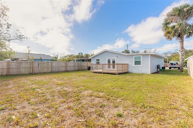 rear view of property featuring a lawn and a deck