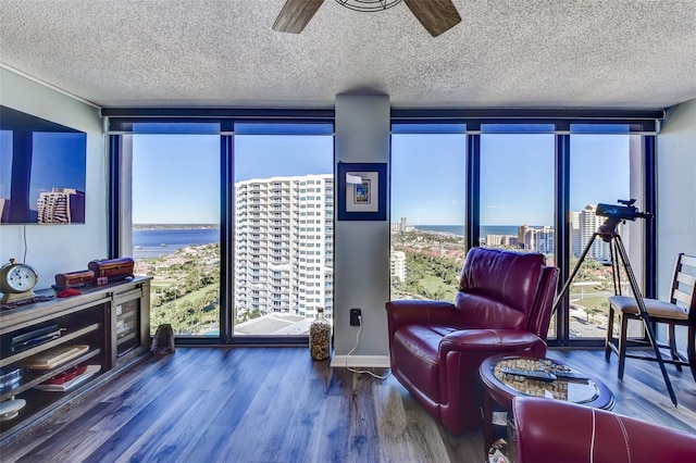 sitting room with floor to ceiling windows, wood-type flooring, a water view, and ceiling fan