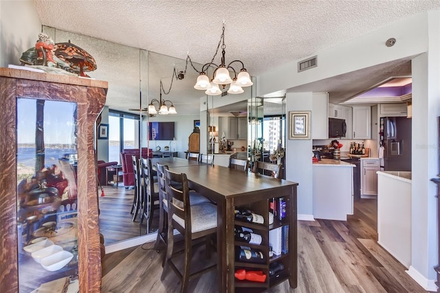 dining room with hardwood / wood-style floors, a textured ceiling, and an inviting chandelier