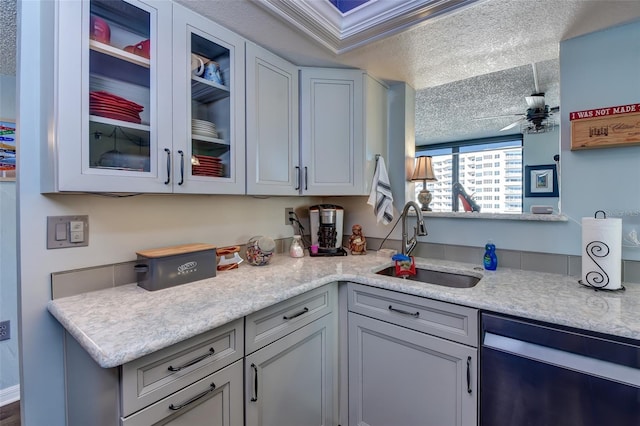 kitchen featuring light stone counters, stainless steel dishwasher, a textured ceiling, ceiling fan, and sink