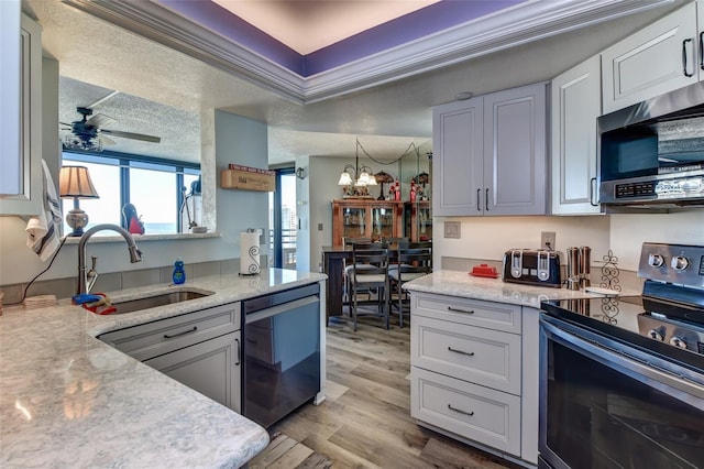 kitchen featuring sink, light hardwood / wood-style flooring, a textured ceiling, ceiling fan with notable chandelier, and appliances with stainless steel finishes