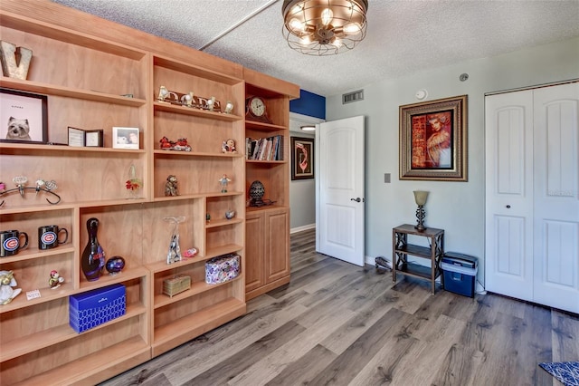 misc room featuring an inviting chandelier, a textured ceiling, and hardwood / wood-style flooring