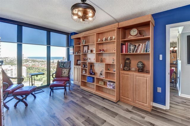 sitting room featuring hardwood / wood-style floors, a water view, and a textured ceiling