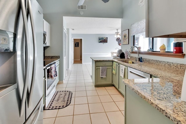 kitchen with sink, stainless steel appliances, kitchen peninsula, light tile patterned floors, and green cabinetry