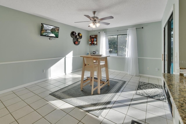 unfurnished dining area with ceiling fan, light tile patterned floors, and a textured ceiling