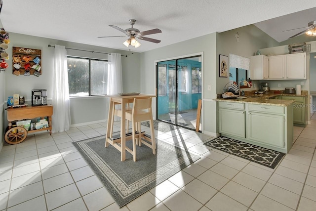 dining room featuring ceiling fan, light tile patterned floors, a textured ceiling, and vaulted ceiling