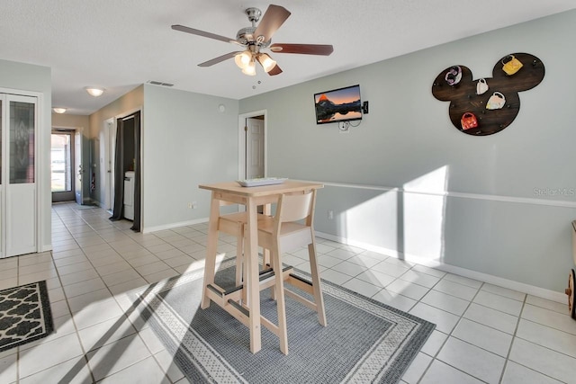 dining area featuring ceiling fan, light tile patterned flooring, and a textured ceiling