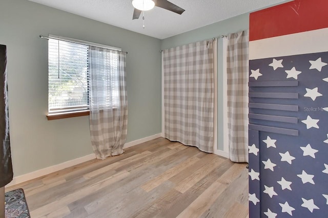 spare room featuring ceiling fan, light hardwood / wood-style floors, and a textured ceiling