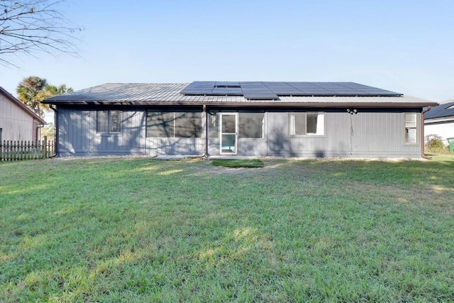 back of house with a lawn and solar panels