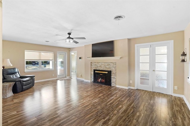 unfurnished living room featuring ceiling fan, a stone fireplace, wood-type flooring, and french doors