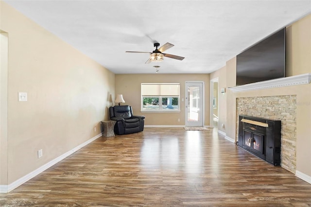 unfurnished living room featuring hardwood / wood-style flooring, a stone fireplace, and ceiling fan