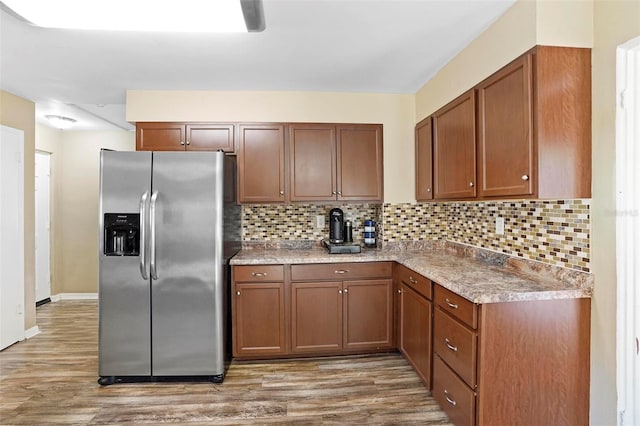 kitchen featuring decorative backsplash, stainless steel refrigerator with ice dispenser, and hardwood / wood-style floors