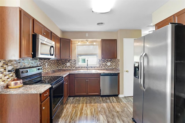 kitchen with decorative backsplash, appliances with stainless steel finishes, sink, and hardwood / wood-style floors