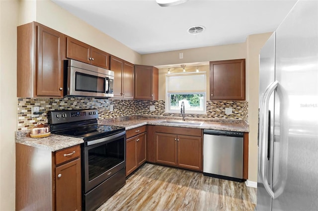 kitchen featuring backsplash, light hardwood / wood-style floors, sink, and appliances with stainless steel finishes