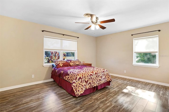 bedroom with ceiling fan, dark hardwood / wood-style flooring, and multiple windows