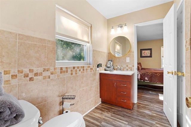 bathroom with wood-type flooring, vanity, toilet, and tile walls