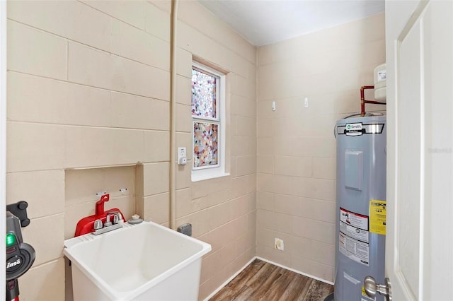 laundry area featuring electric water heater, dark wood-type flooring, and sink