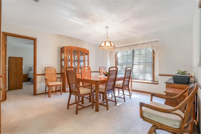 dining room featuring a notable chandelier, light colored carpet, and a textured ceiling