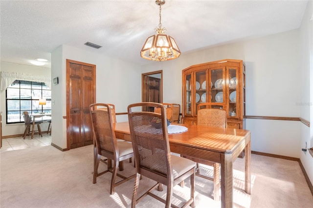 dining area with a textured ceiling, light carpet, and a chandelier