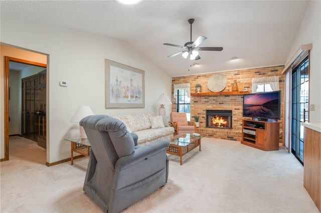 carpeted living room with a fireplace, vaulted ceiling, a wealth of natural light, and ceiling fan