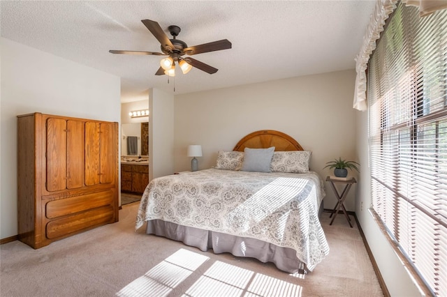 carpeted bedroom featuring ensuite bathroom, ceiling fan, and a textured ceiling