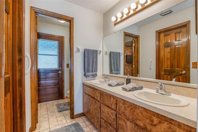 bathroom with tile patterned flooring, vanity, a textured ceiling, and toilet