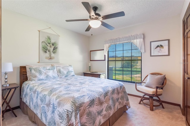 bedroom featuring ceiling fan, light carpet, and a textured ceiling