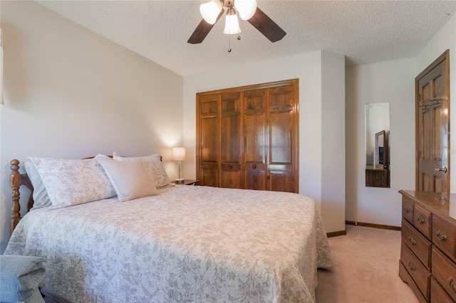 bedroom with ceiling fan, a textured ceiling, light carpet, and a closet